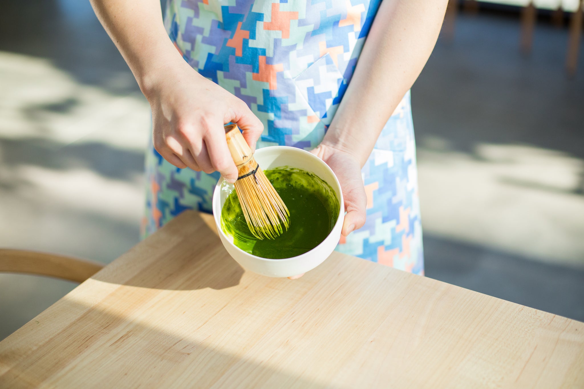 person whisking matcha in a white bowl