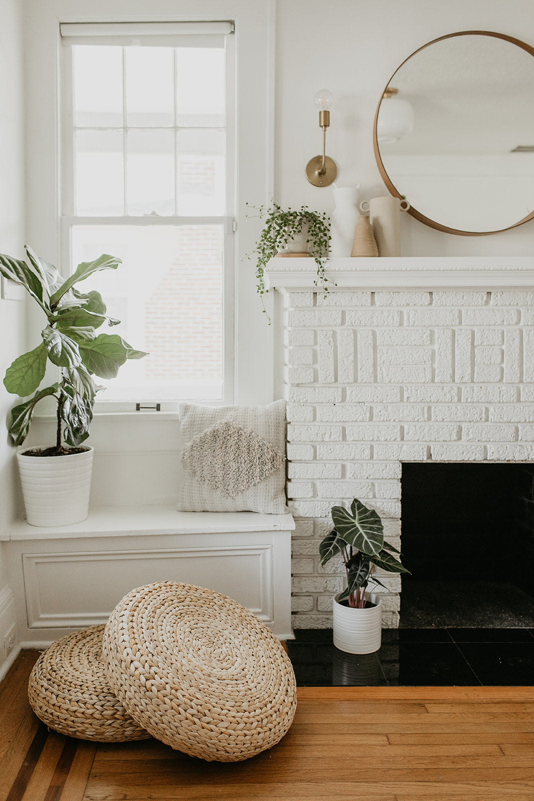 white fireplace with a mirror above it next to a window