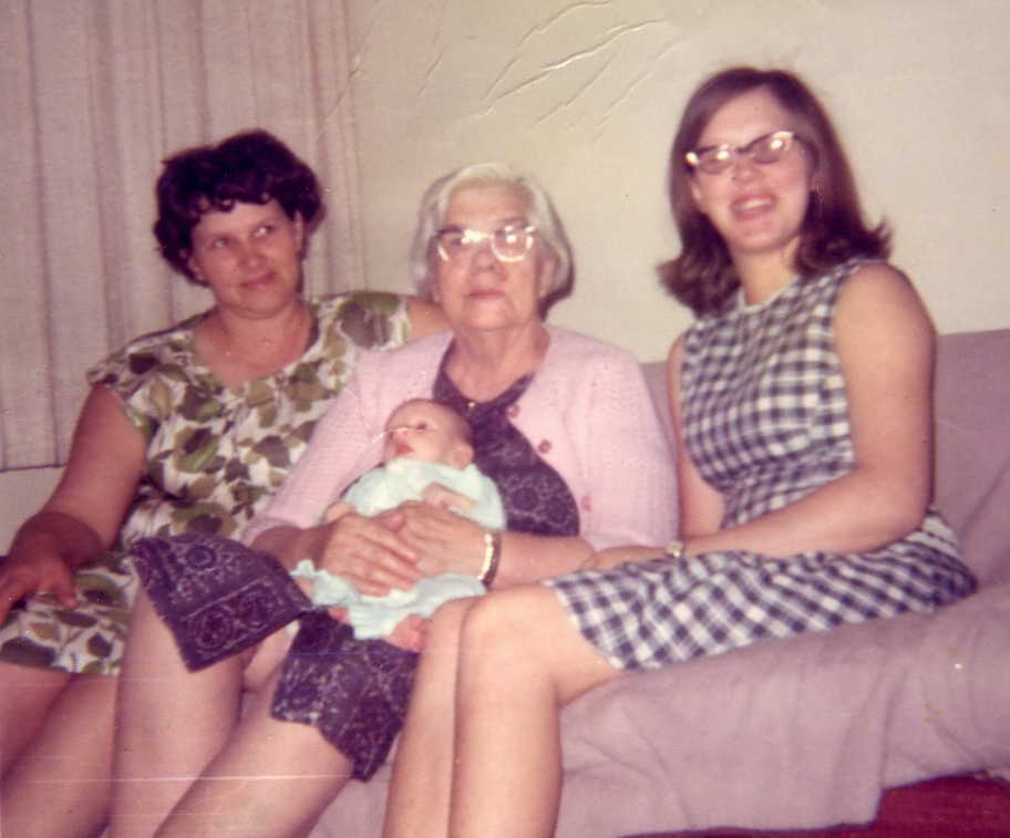 group of women sitting on a couch holding a baby