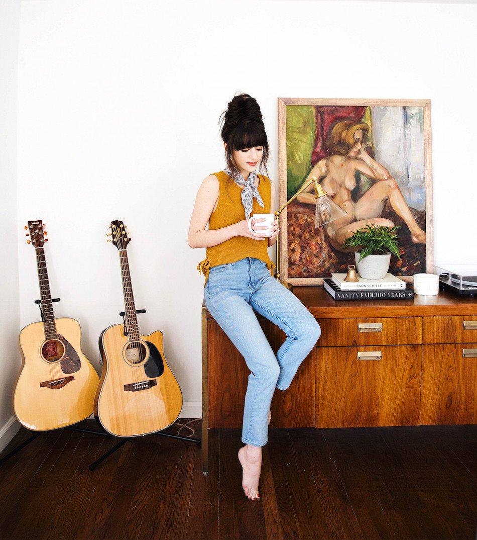 person in front of a cabinet next to two guitars