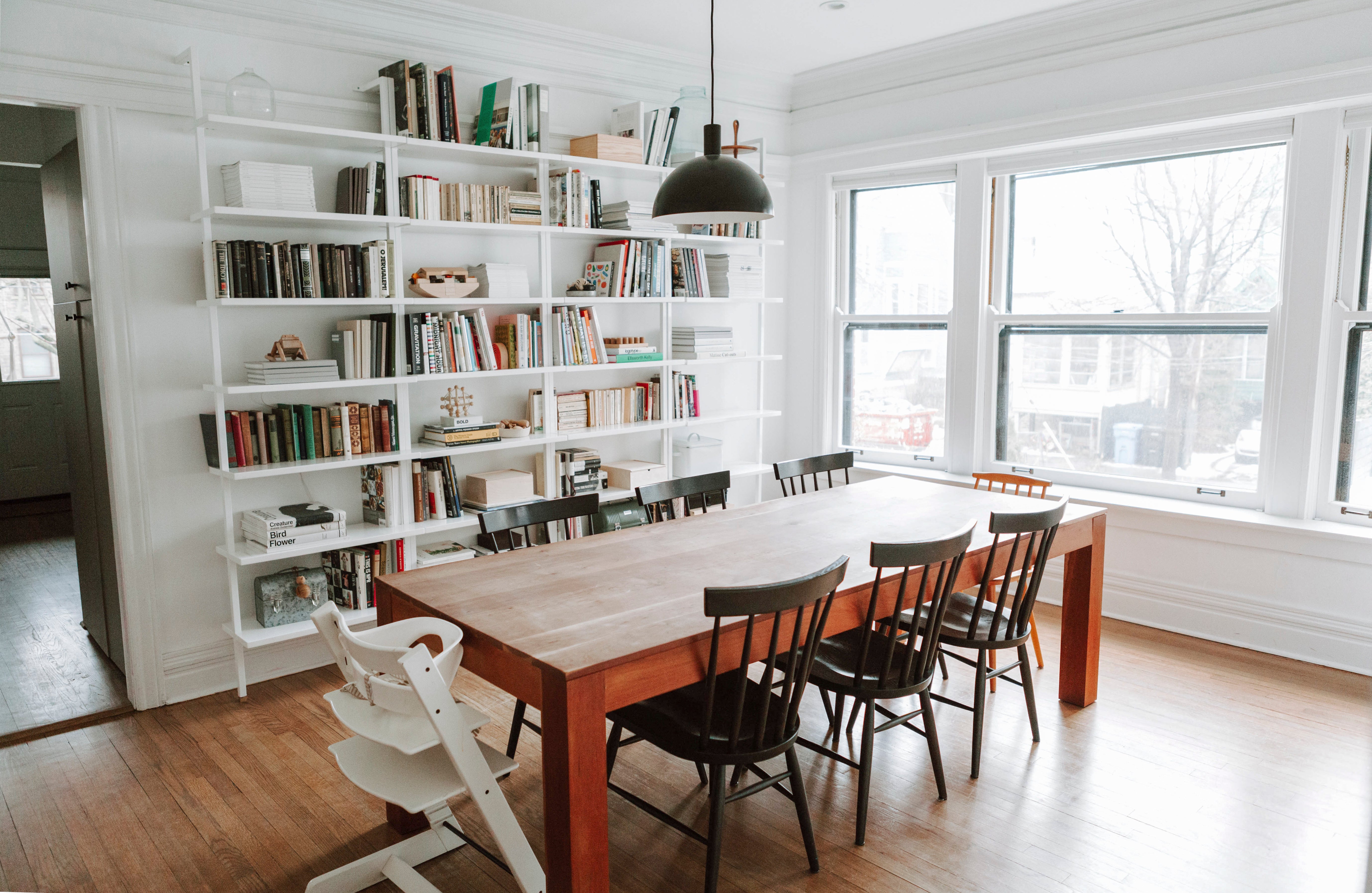 room with a table and chairs and a black ceiling light fixture and book shelves