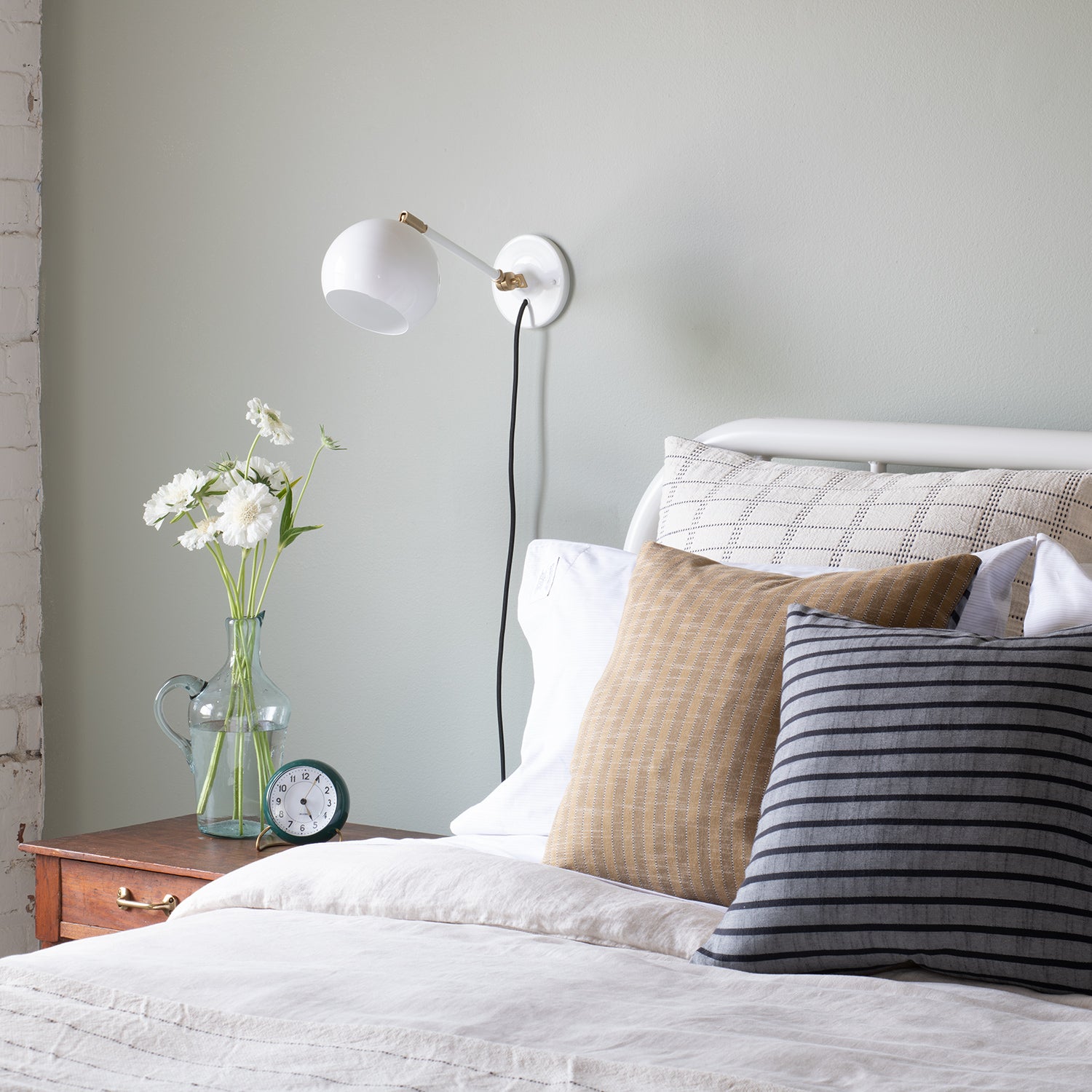 bed with a white sconce and pillows
