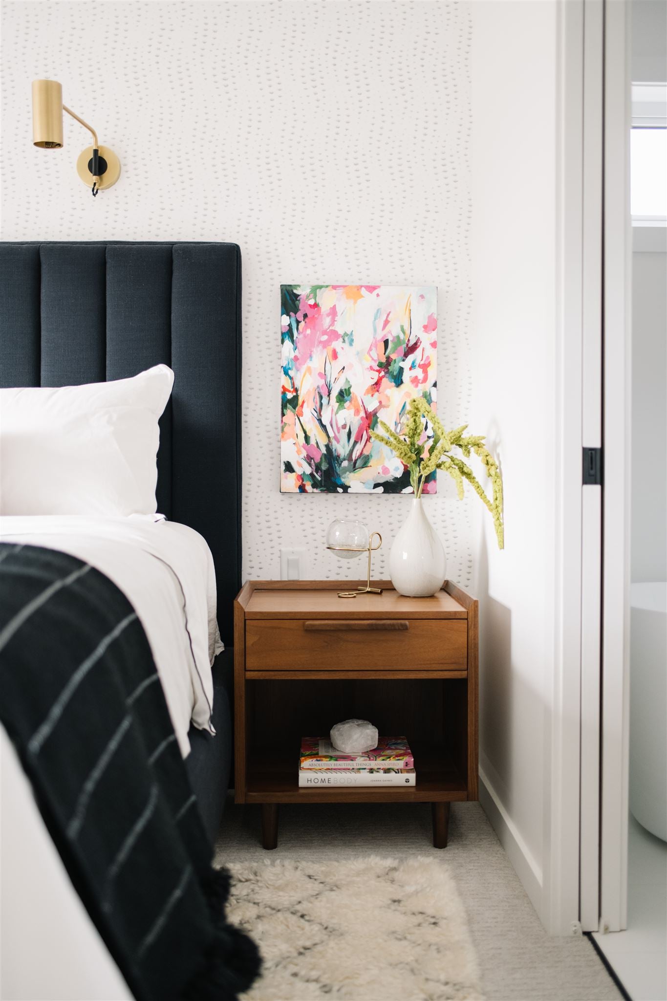 bed with dark bed spread and white pillows and nightstand