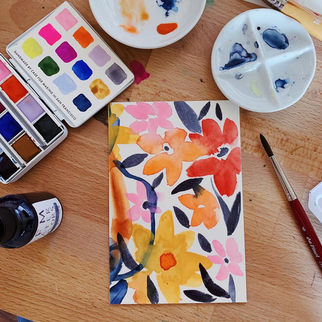 table with a painting of flowers and watercolor paint