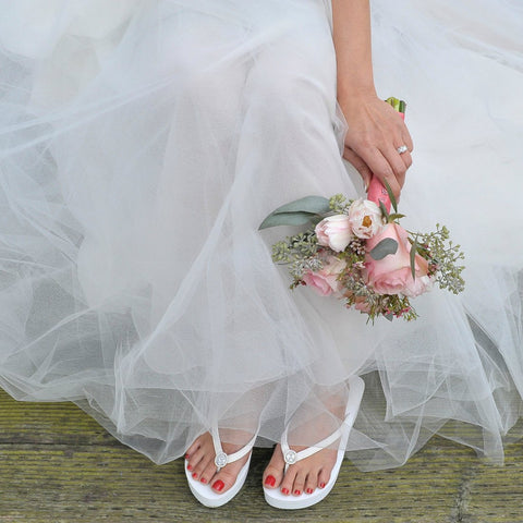 Bride wearing white flip flops with vintage diamond ring
