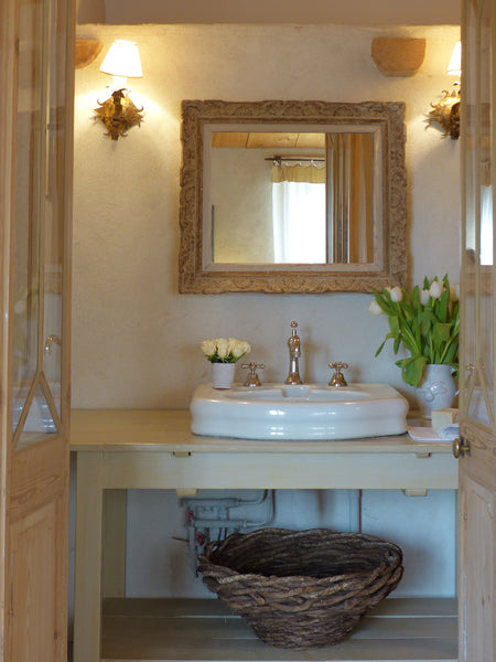 French woven basket under bathroom basin with antique mirror