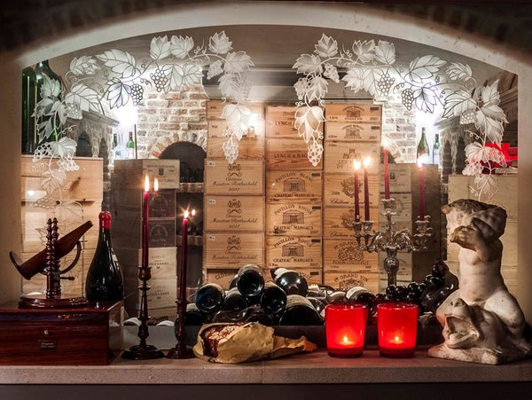Wine cellar with antique and vintage candlesticks make it a fun and moody space - Walda Pairon
