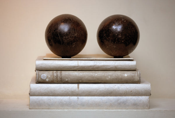 Petanque balls sit on top of vintage books with neutral palette - Walda Pairon