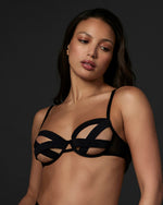 Model wearing the underwired Emilia black caged bra with a triple crossover strap cup and caged design for the ultimate, sexy look.