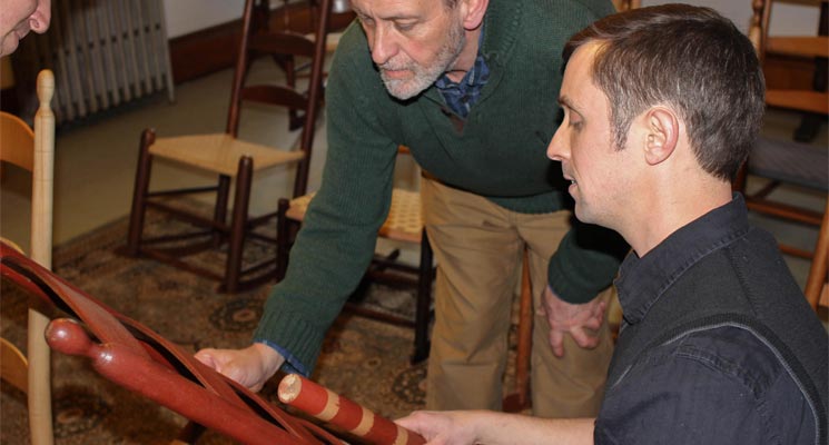 Brother Arnold Hadd and Adam Nudd-Homeyer examine one of the original Alfred Chairs and discuss paint selection. Photo: Sean Hurley