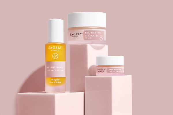 Sagely Naturals Brightening CBD Skincare collection positioned on pink blocks against a pink backdrop