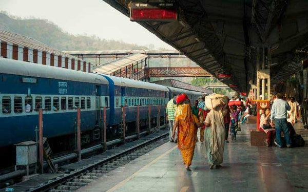 Train station in India with people on the platform coming and going.