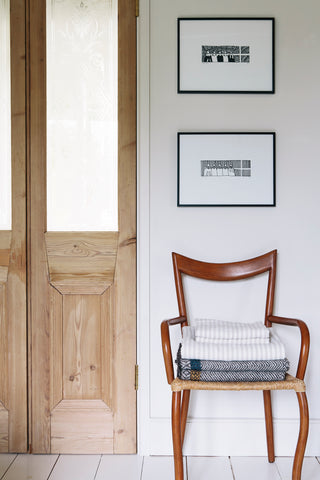 A chair next to a wooden door has striped linen and a blanket on it 