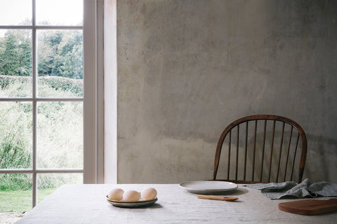 a table with a linen table cloth is sparsely laid with a plate of eggs