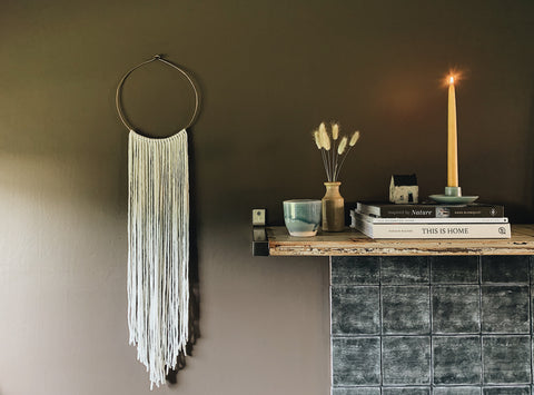 Brown walls with macrame and mantlepiece with trinkets