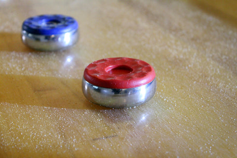 A red and blue shuffleboard puck on a waxed shuffleboard table.