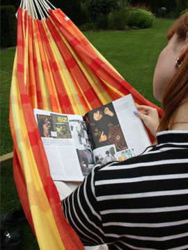 Woman in hammock reading magazine