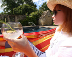 Woman in hammock holding glass of gin by pool