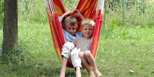 Two children sat in hanging hammock chair