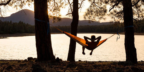 Man sitting in travel hammock overlooking lake