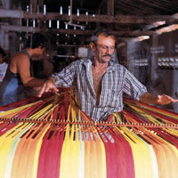 Man at loom weaving fabric for hammocks