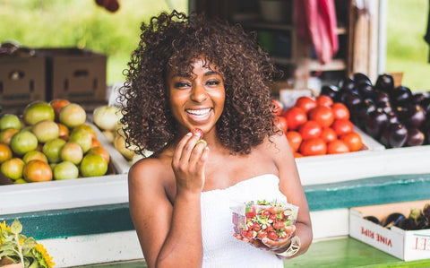 Black woman with curly hair eating fruit