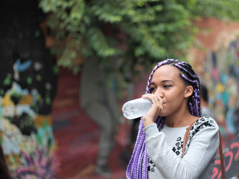 Black woman with protective style braids drinking water