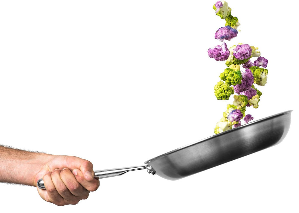 Skillet vs. pan: a hand flips cauliflower in a skillet