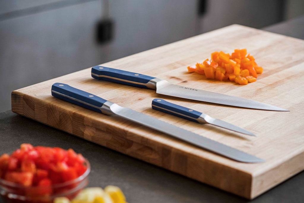 Parts of a knife: three knives on a cutting board with diced carrots