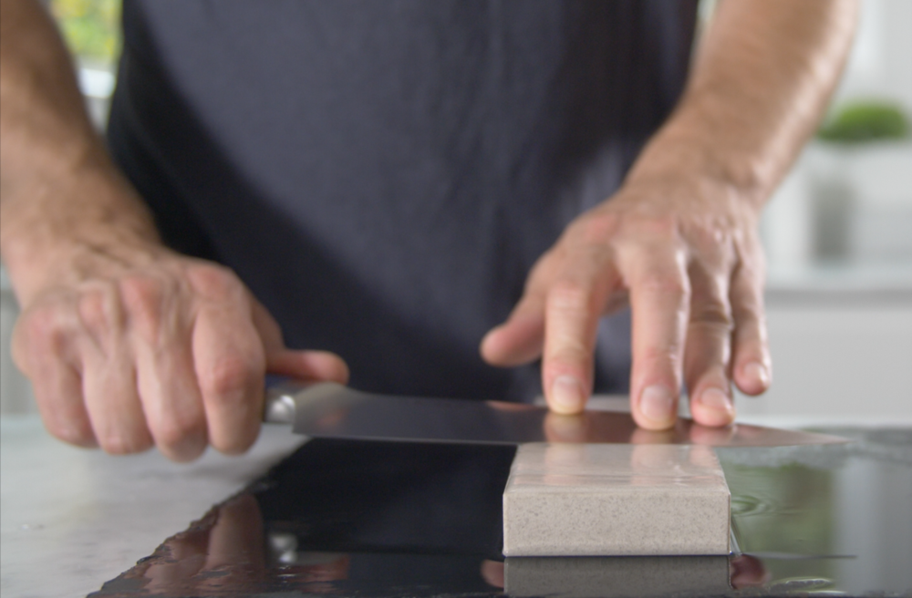 A man sharpens a knife on a Japanese water stone