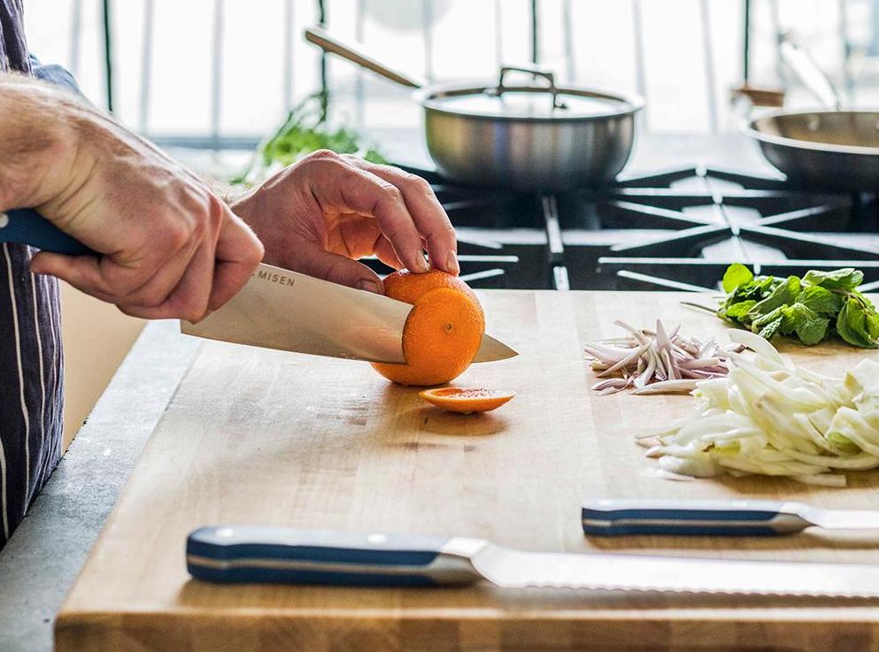 A chef slices an orange in a kitchen setting
