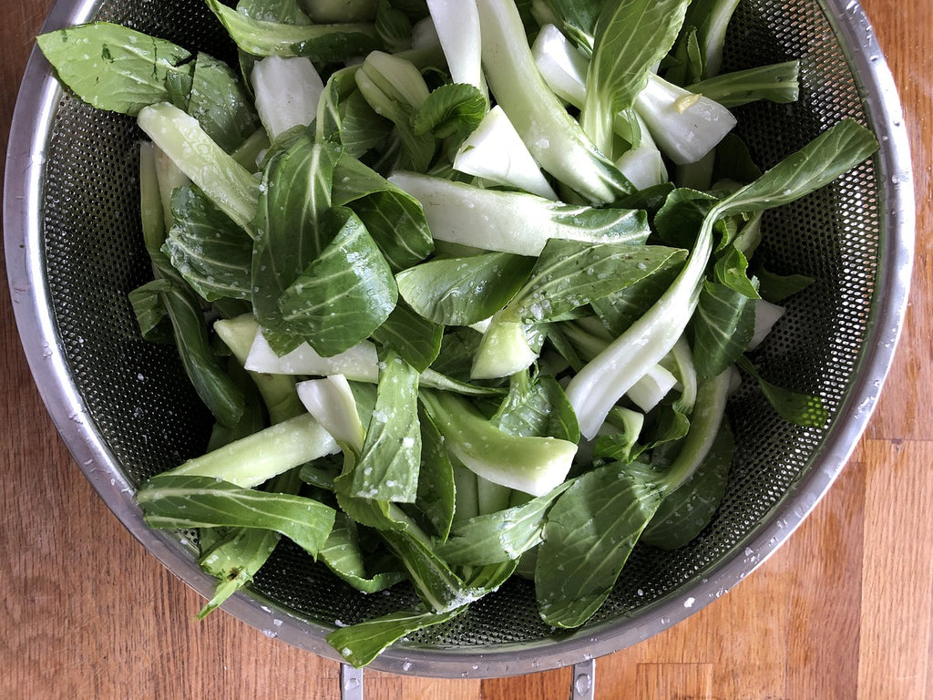 How to cut bok choy: Whole leaves of baby bok choy in a colander