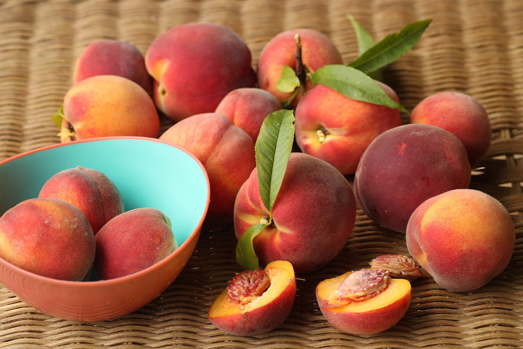 How to cut a peach: a group of peaches with some sliced and some in a bowl