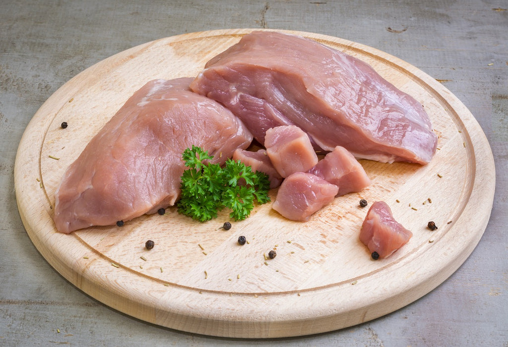 Raw chicken on a round wood cutting board