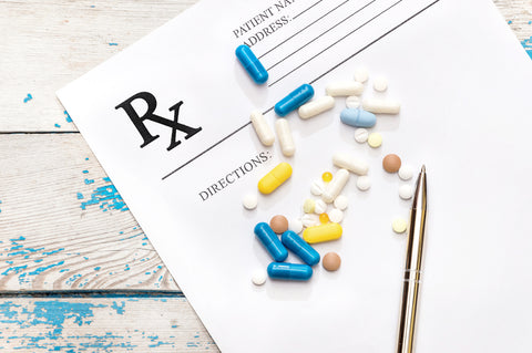 Multi-colored pills and a pen sit on a prescription pad