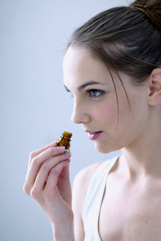 A woman holds an essential oil bottle to her nose