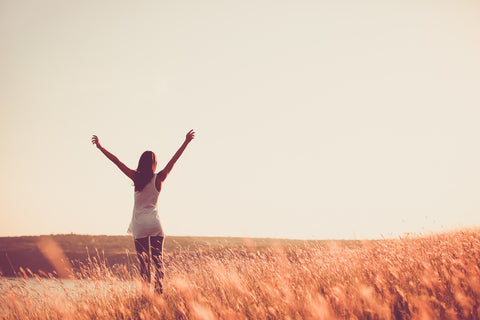 Woman stretching her arms over her head in a wheat field