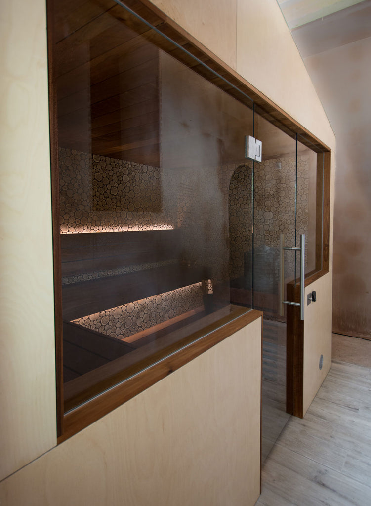 When it came to the outside of the sauna, the focus instead turned to make sure the sauna’s aesthetic fit in well with the surrounding space. External cladding of lacquered birch ply sheet produced a sleek, modern, and airy appearance that suited the surrounding space.