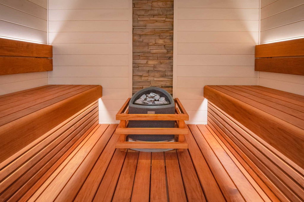 Using a pale white timber on the sauna walls helps to brighten the space. The cladding is arranged horizontally which mirrors the benching and gives the eye a more inviting aesthetic, leading the centrepiece sauna heater.