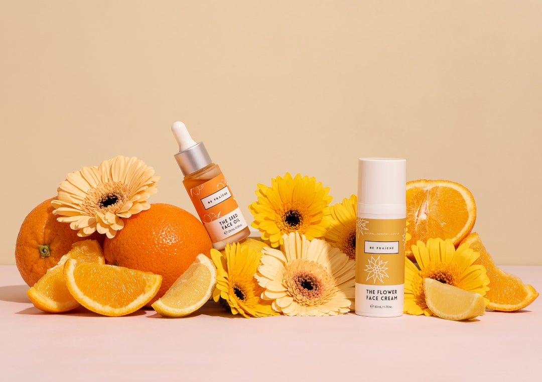 Be Fraiche Hydration Boost Duo including Seed Face Oil and Flower Face Cream styled with orange and yellow fruits