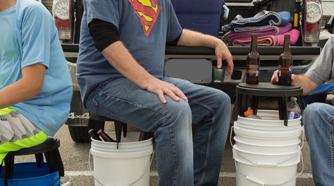 Three people pictured using The Original Bucket Stool™ for tailgating at a sporting event. Click to see tailgating solutions page.