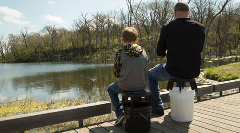 Father and son each using The Original Bucket Stool™ for fishing. Click to see outdoor solutions page.