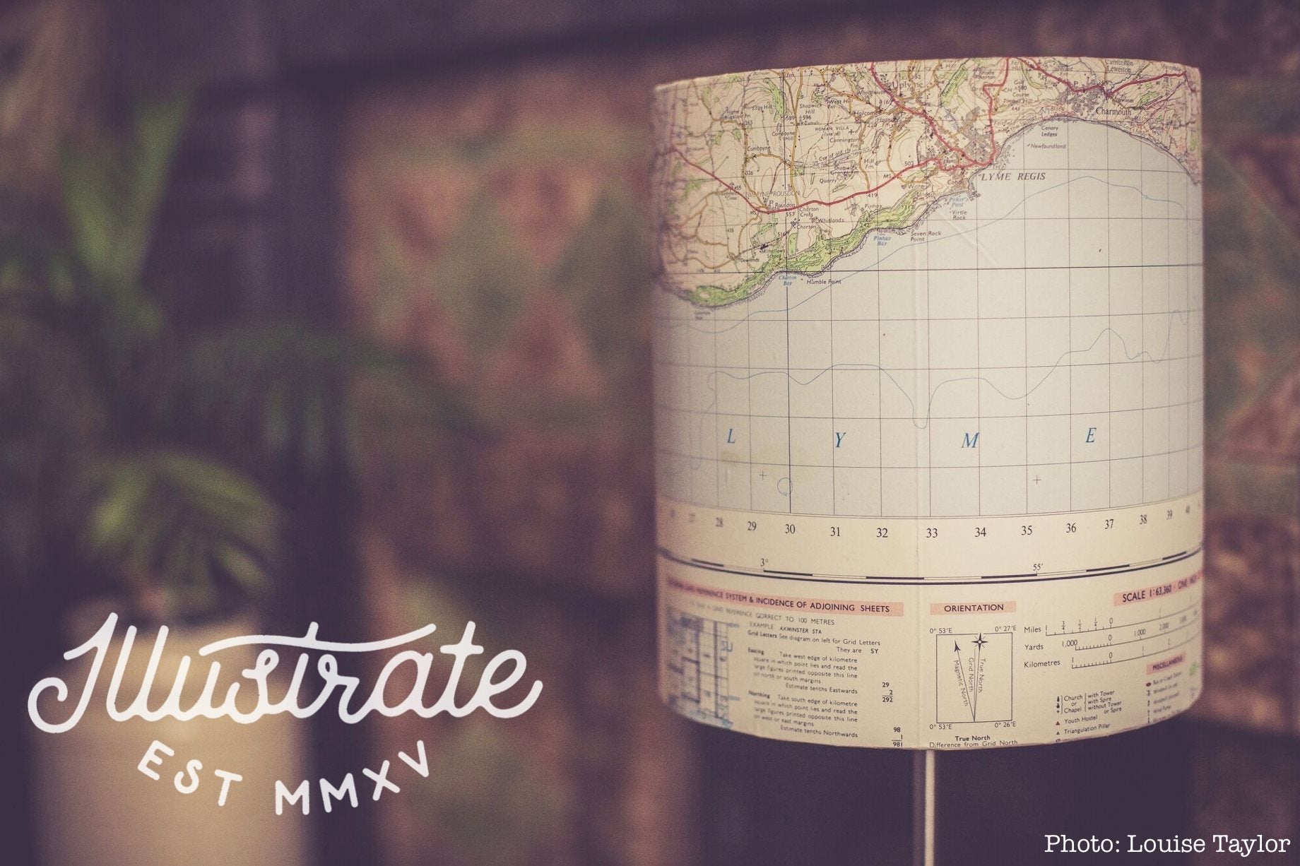 A DIY lampshade made from an upcycled old map, Illustrate's cursive logo (bottom left)