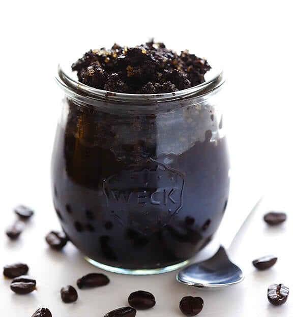Home made coffee body scrub in jar surrounded by coffee beans