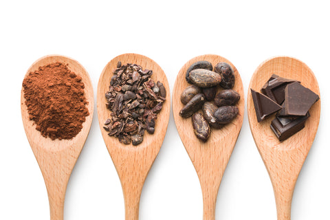 Spoonfuls of Cacao Powder, Cacao Nibs, Chocolate Covered Cacao Beans, and Dark Chocolate Bars