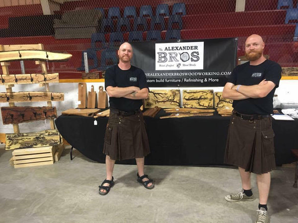 Two men wear utility kilts made while showcasing their wares at a crafts show