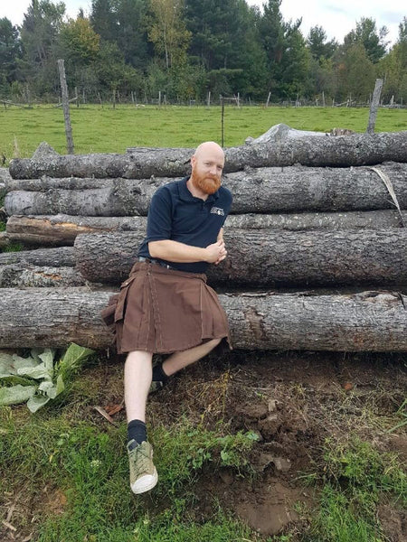 A burly Canadian lumberjack putting out the vibe while reclining on a stack of logs