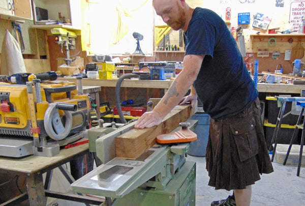 craftsman saws lumber while wearing a utility kilt from kilt brand Damn Near Kilt Em