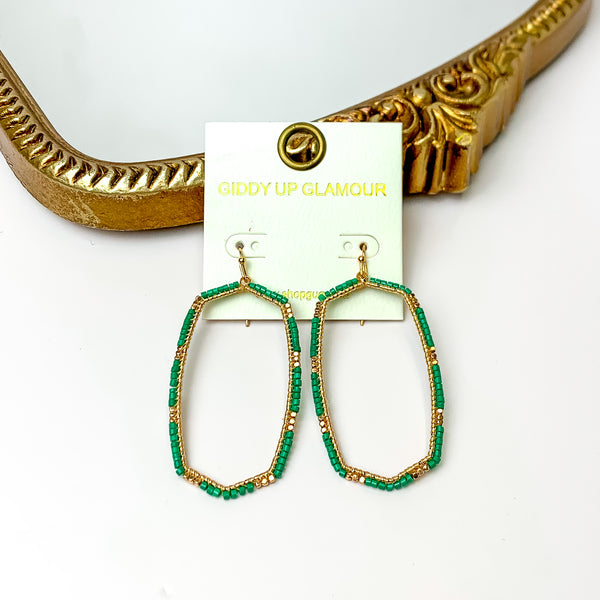 Green Beaded Open Large Drop Earrings with Gold Tone Accessory. Pictured on a white background with a gold frame through it.