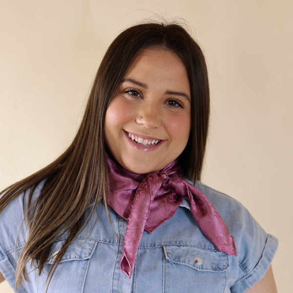 Brunette model is pictured wearing a Blue Dress with a wine colored Jacquard scarf tied around her neck. Model is pictured in front of a beige background. 